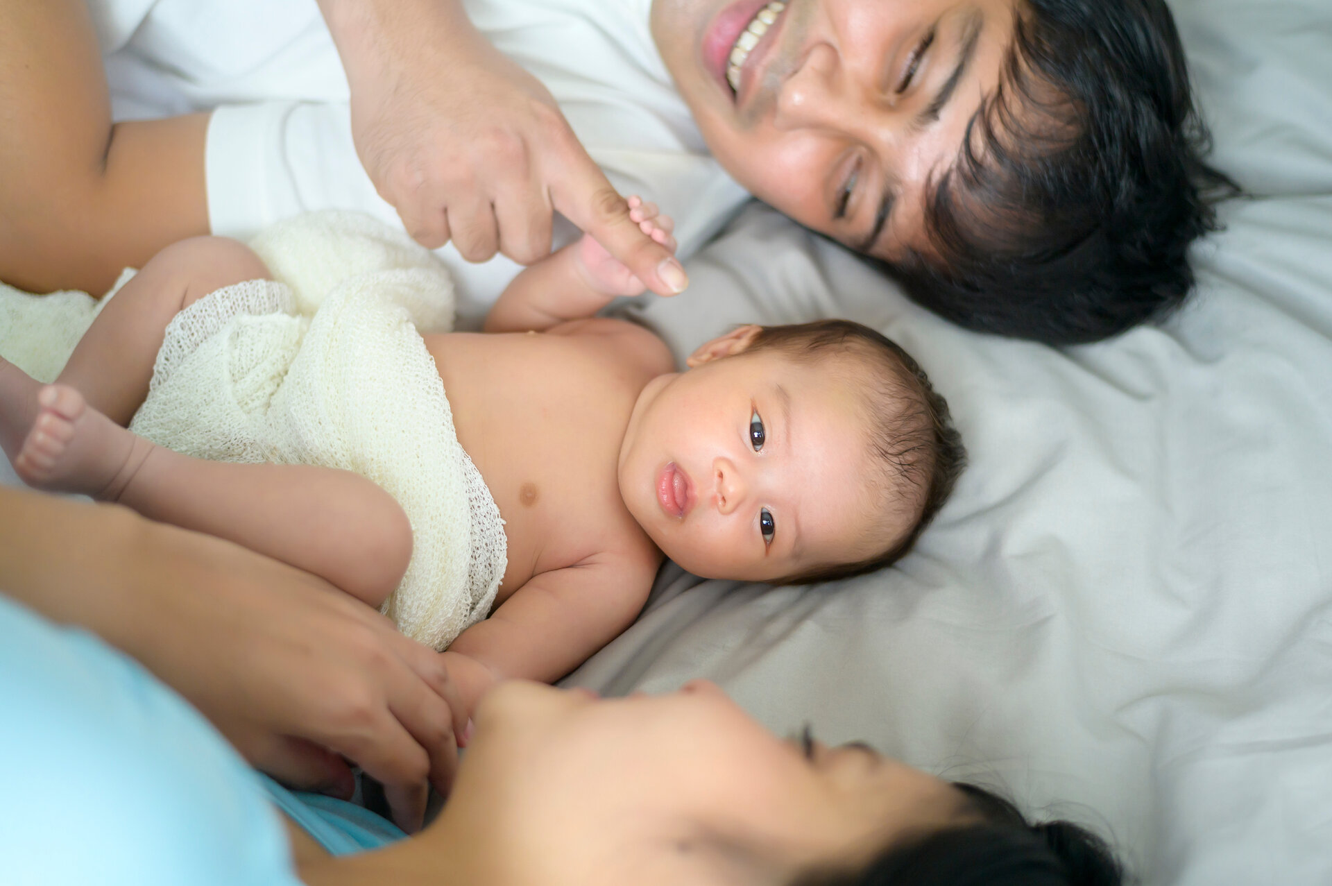 Lächelnde junge Mutter und Vater mit einem neugeborenen Baby